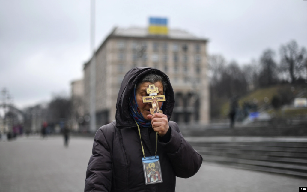 Женщина держит крест во время молитвы на майдане Независимости в Киеве утром 24 февраля